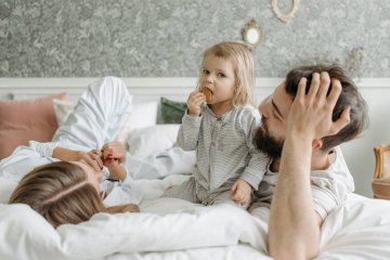 Rodzice bawią się na łóżku z dzieckiem.