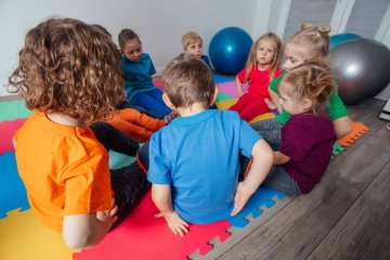 Dzieci bawią się ze sobą w sali przedszkolnej.