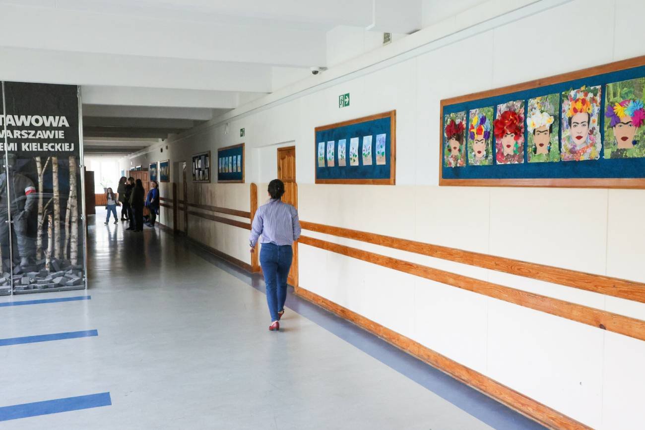 Nauczycielka idzie szkolnym korytarzem.