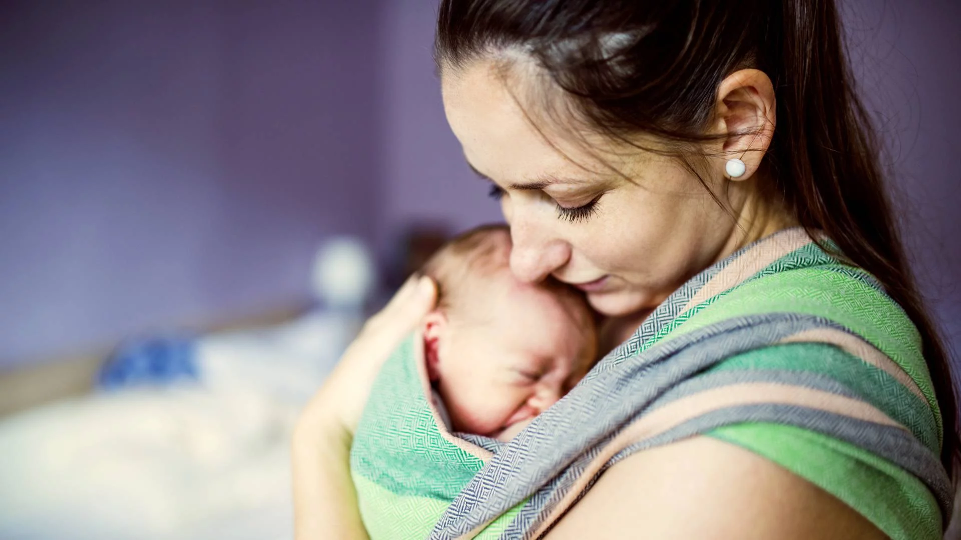 matka trzyma w chuście niemowlę i przytula je matka trzyma w chuście niemowlę i przytula je