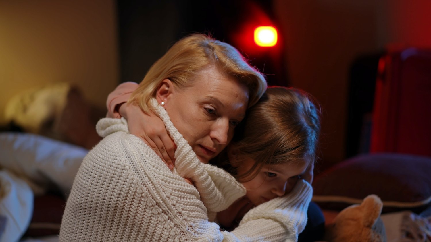 Matka z depresją jest mniej zaangażowana w wychowanie dziecka. Na zdjęciu mała dziewczynka przytula smutną mamę.