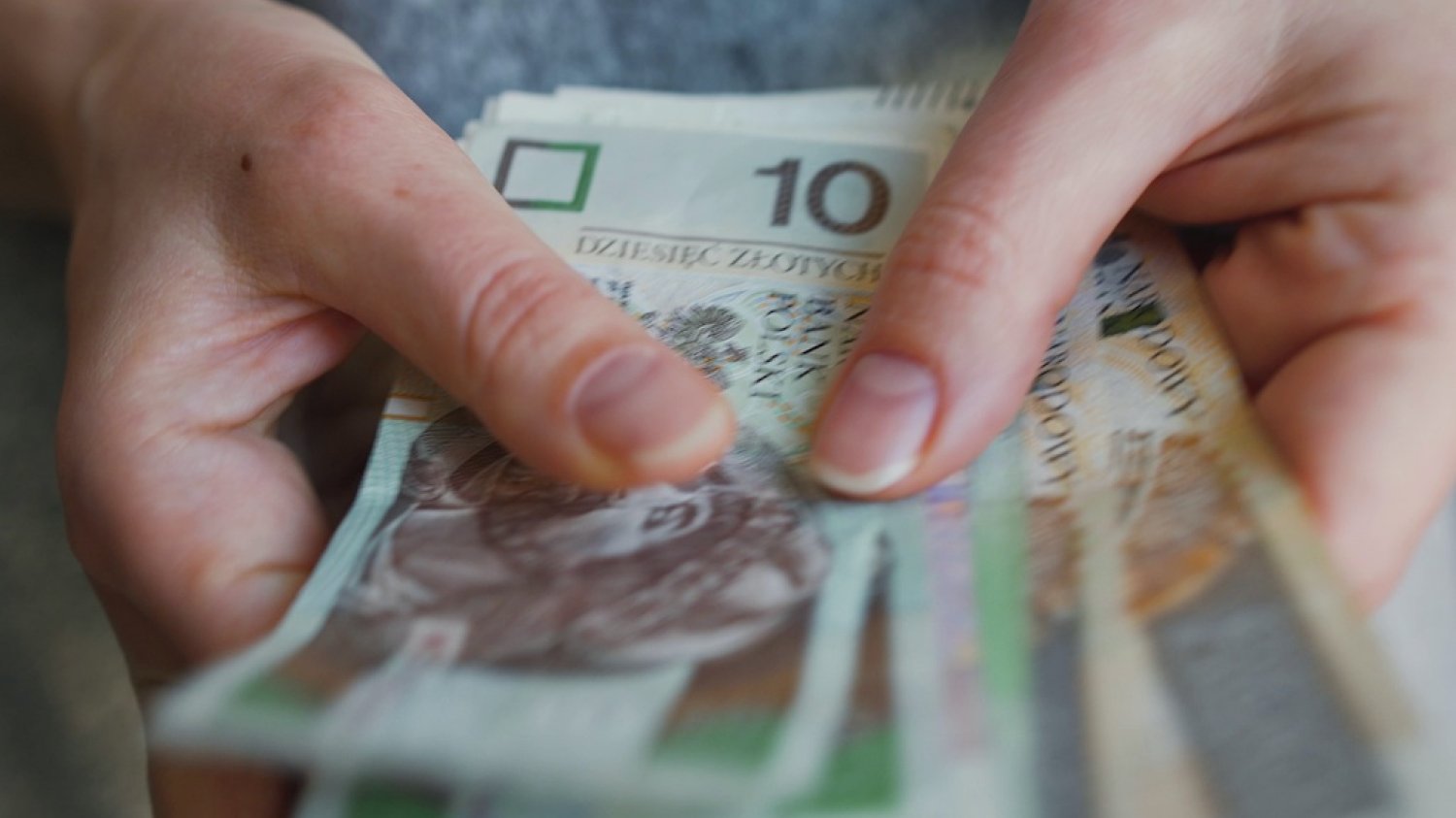 Szkoła jest bezpłatna tylko w teorii. Za co tak naprawdę płacą rodzice? Na zdjęciu widać kobietę trzymającą plik pieniędzy