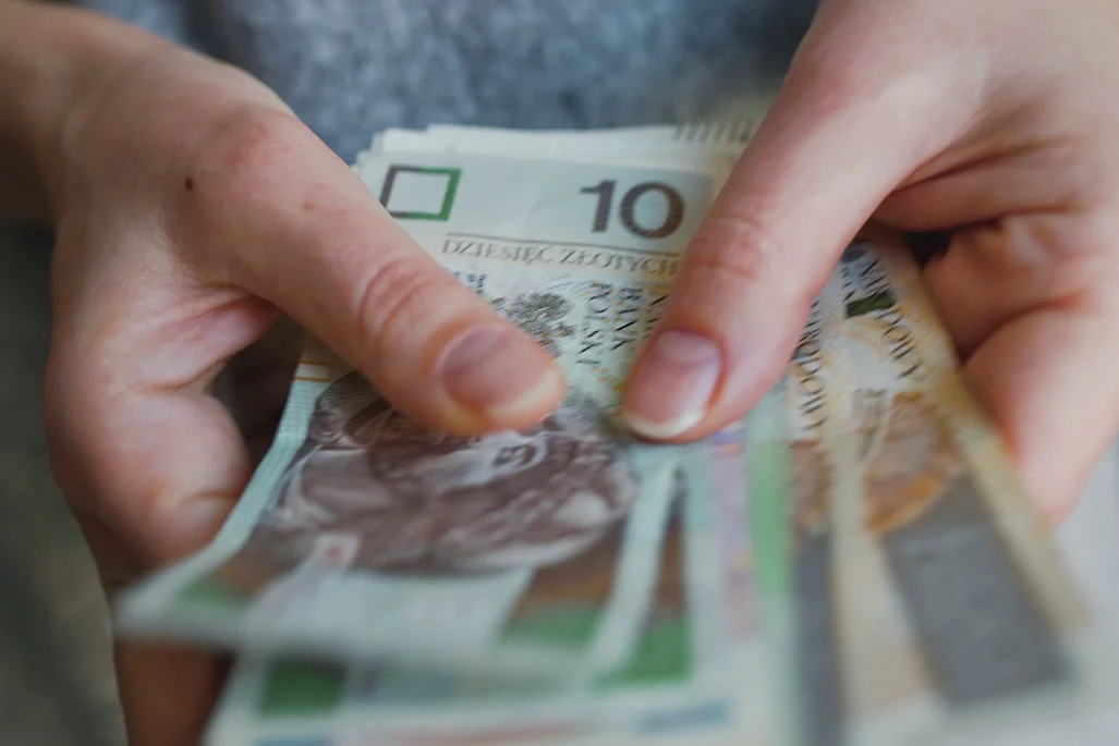 Szkoła jest bezpłatna tylko w teorii. Za co tak naprawdę płacą rodzice? Na zdjęciu widać kobietę trzymającą plik pieniędzy