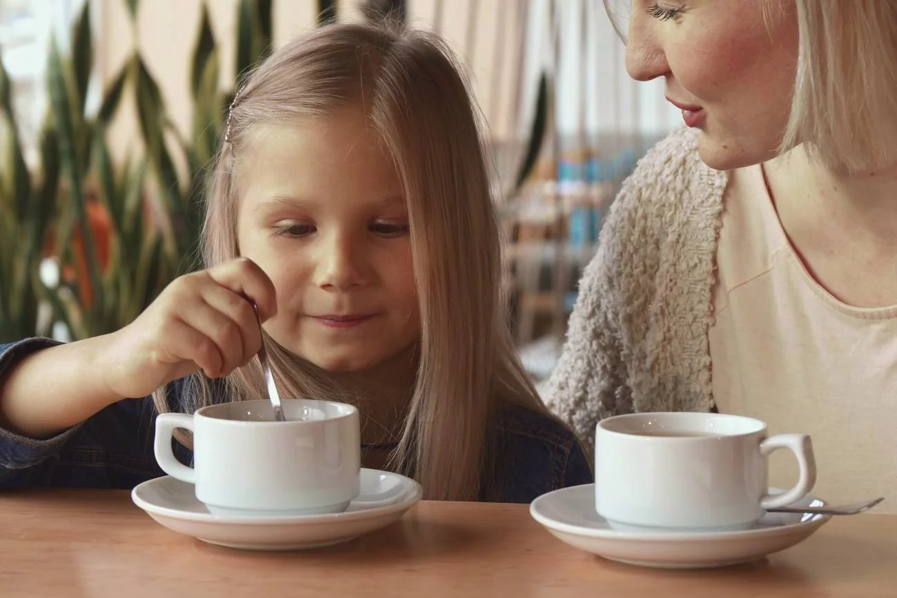 mama z córką siedzą z filiżankami ze złotym mlekiem mama z córką siedzą z filiżankami ze złotym mlekiem