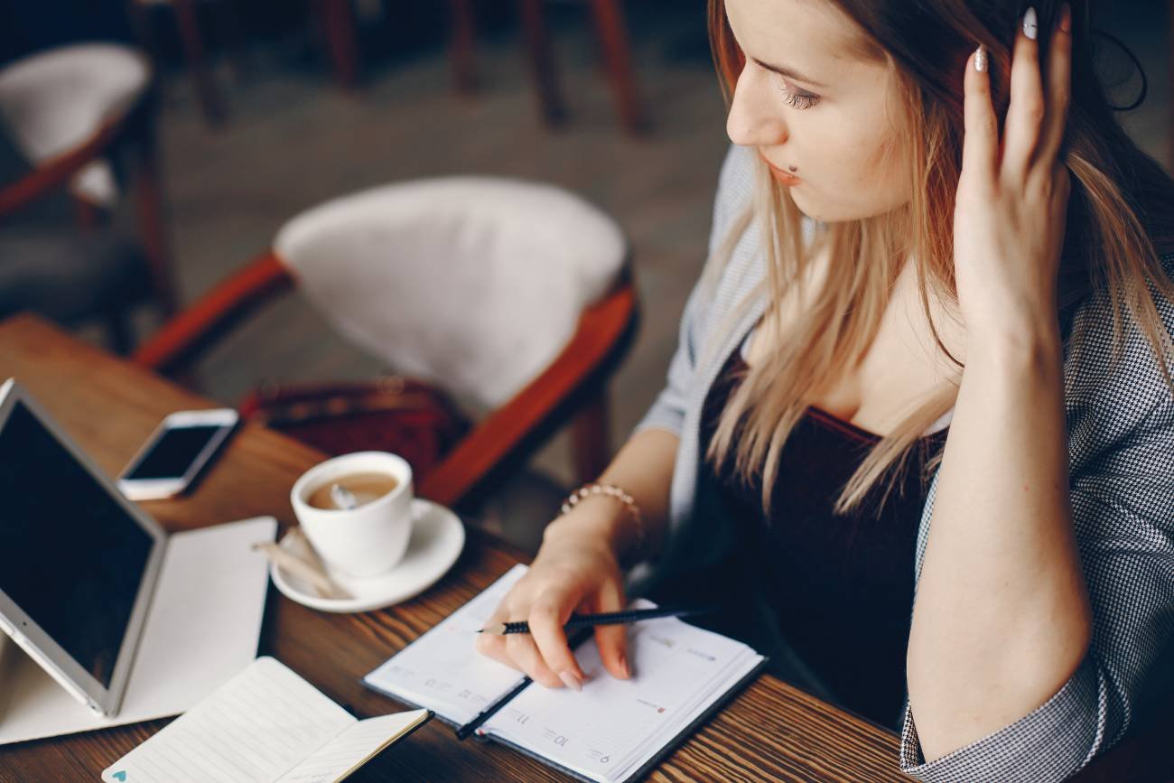 Kobieta planująca urlop w notesie i kalendarzu.