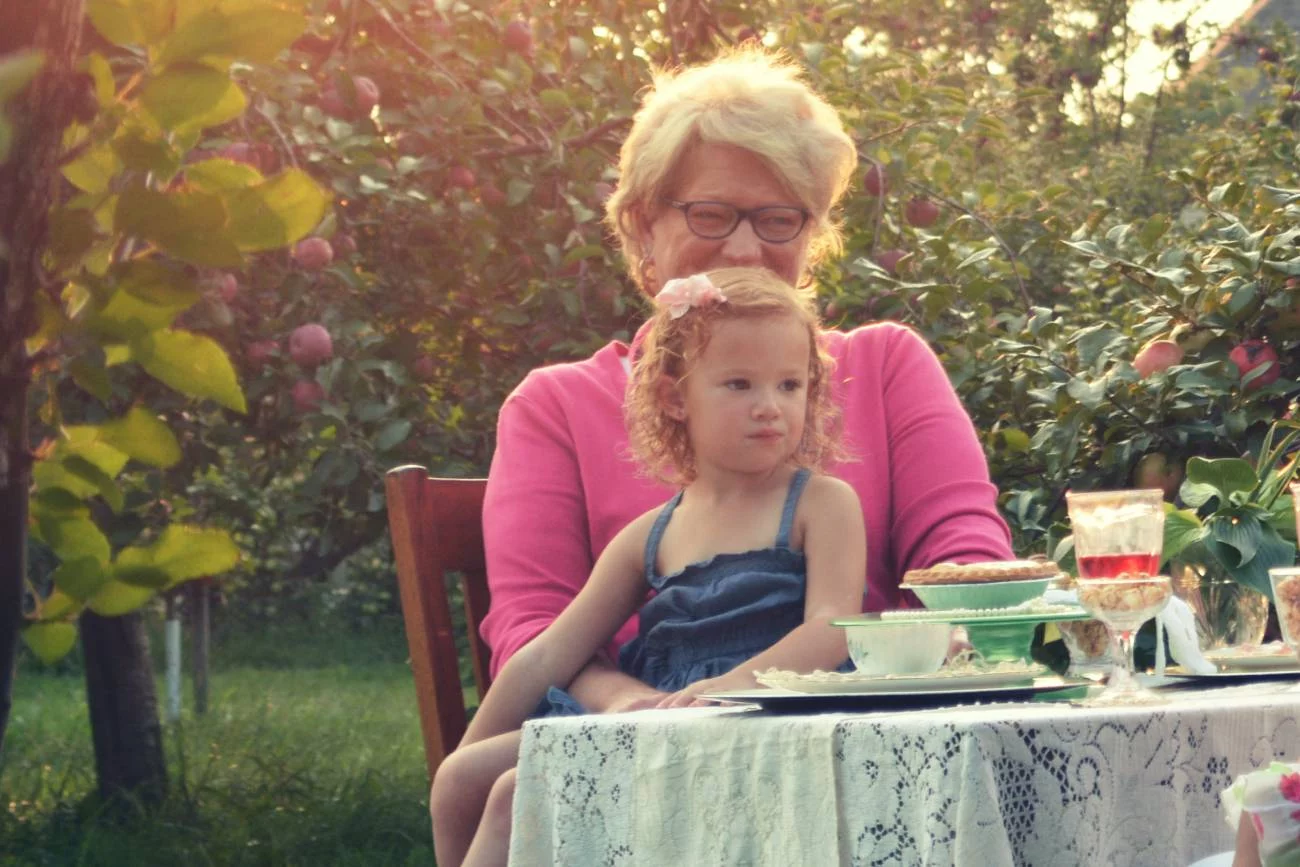 Babcia opiekująca się wnuczką w ogrodzie.