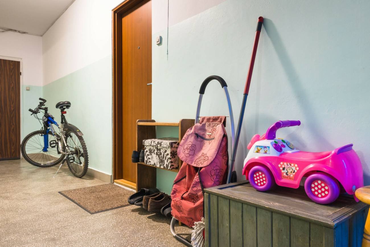 Klatka schodowa w bloku z postawionymi sprzętami.