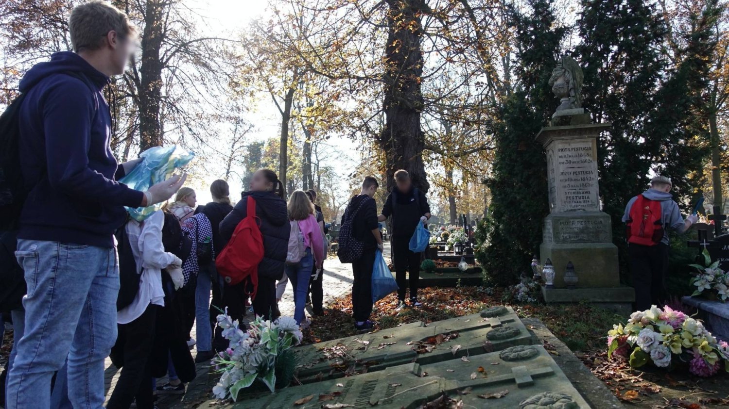 uczniowie na cmentarzu sprzątają na grobach