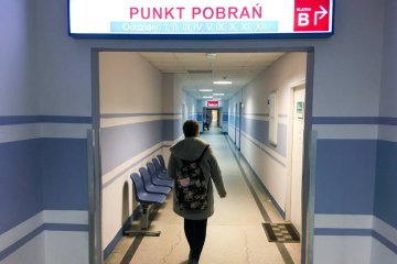 Dziewczyna idzie szpitalnym korytarzem do punktu pobrań na pobranie krwi.