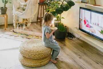 Mała dziewczynka ogląda bajkę na telewizorze.