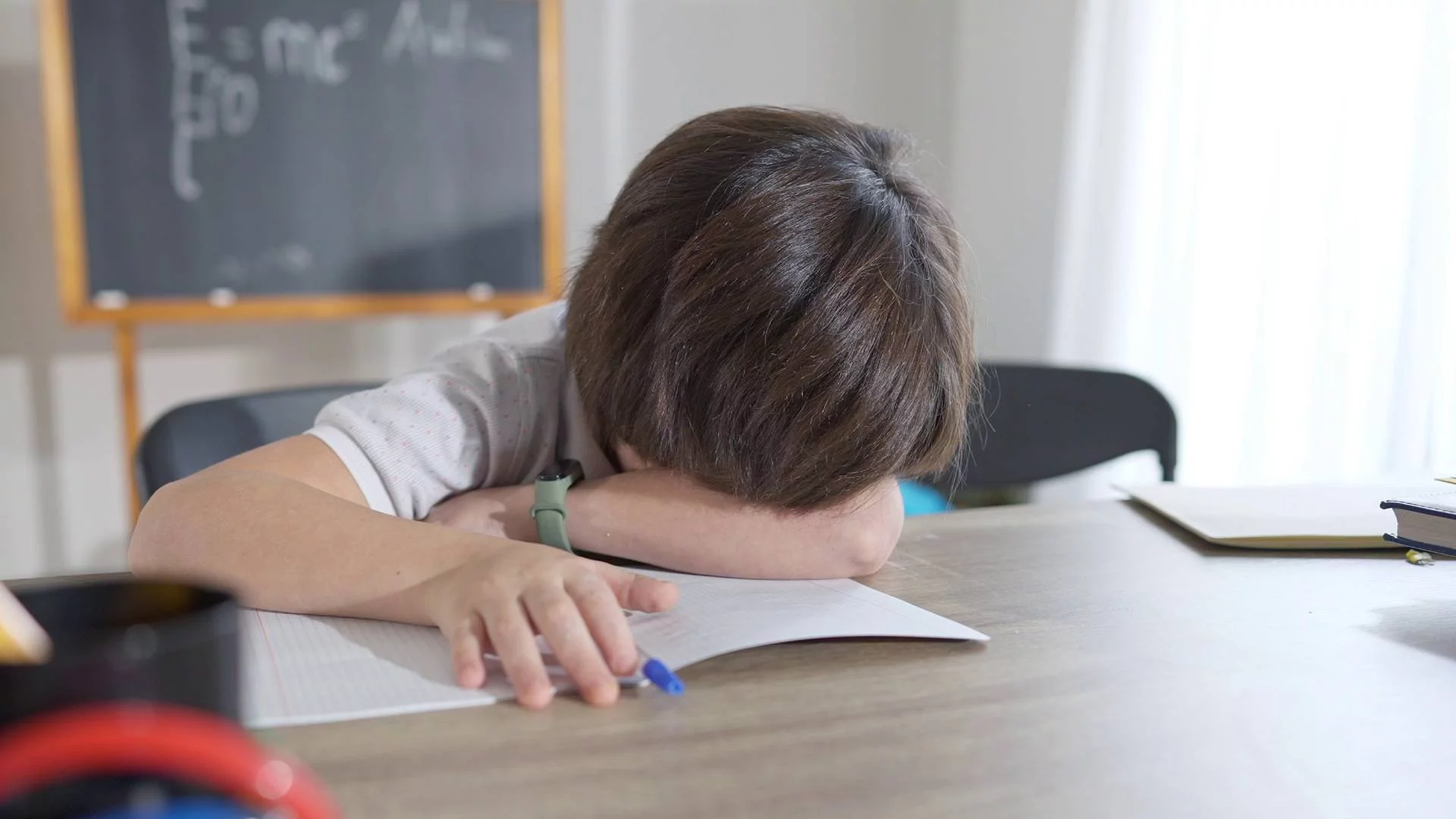 smutny i zły uczeń odrabia lekcje i opiera się czołem na zeszycie smutny i zły uczeń odrabia lekcje i opiera się czołem na zeszycie
