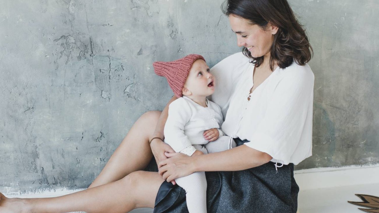 Mama dumna z osiągnięć rozwojowych dziecka, trzyma je na kolanach.