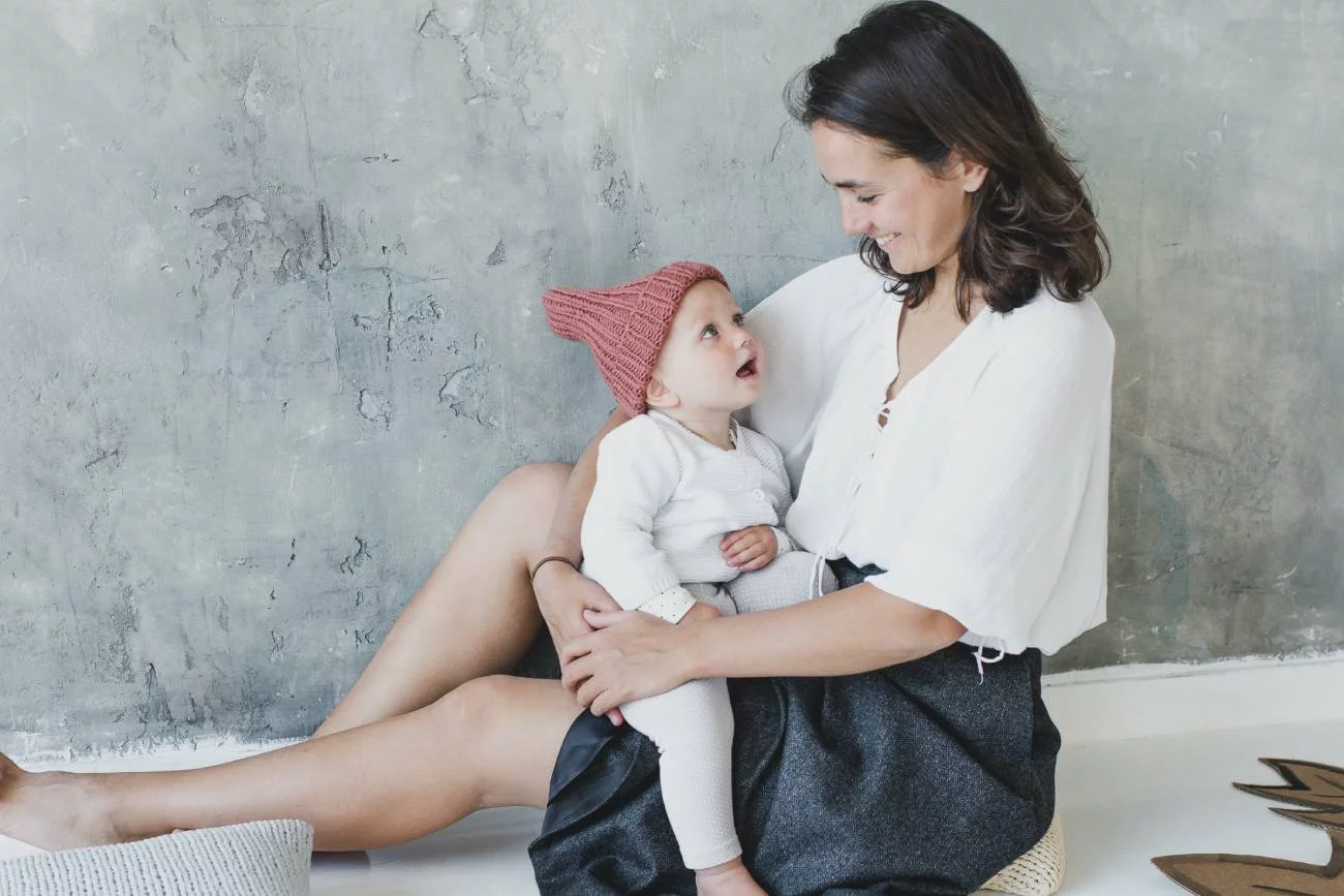 Mama dumna z osiągnięć rozwojowych dziecka, trzyma je na kolanach.