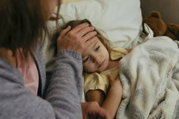 Chora dziewczynka w wieku przedszkolnym leży w łóżku z gorączką.