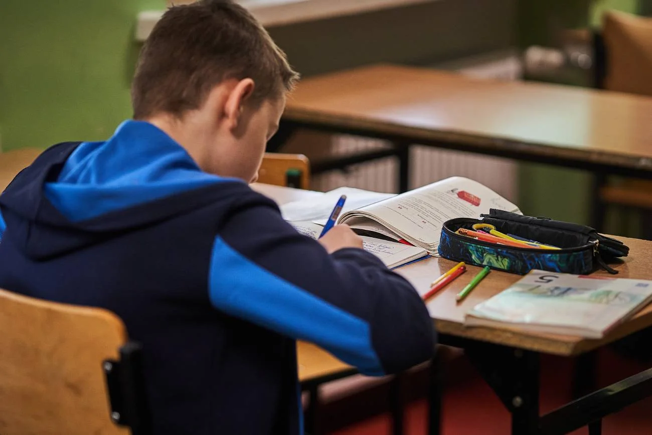 uczeń pisze na lekcji w ławce