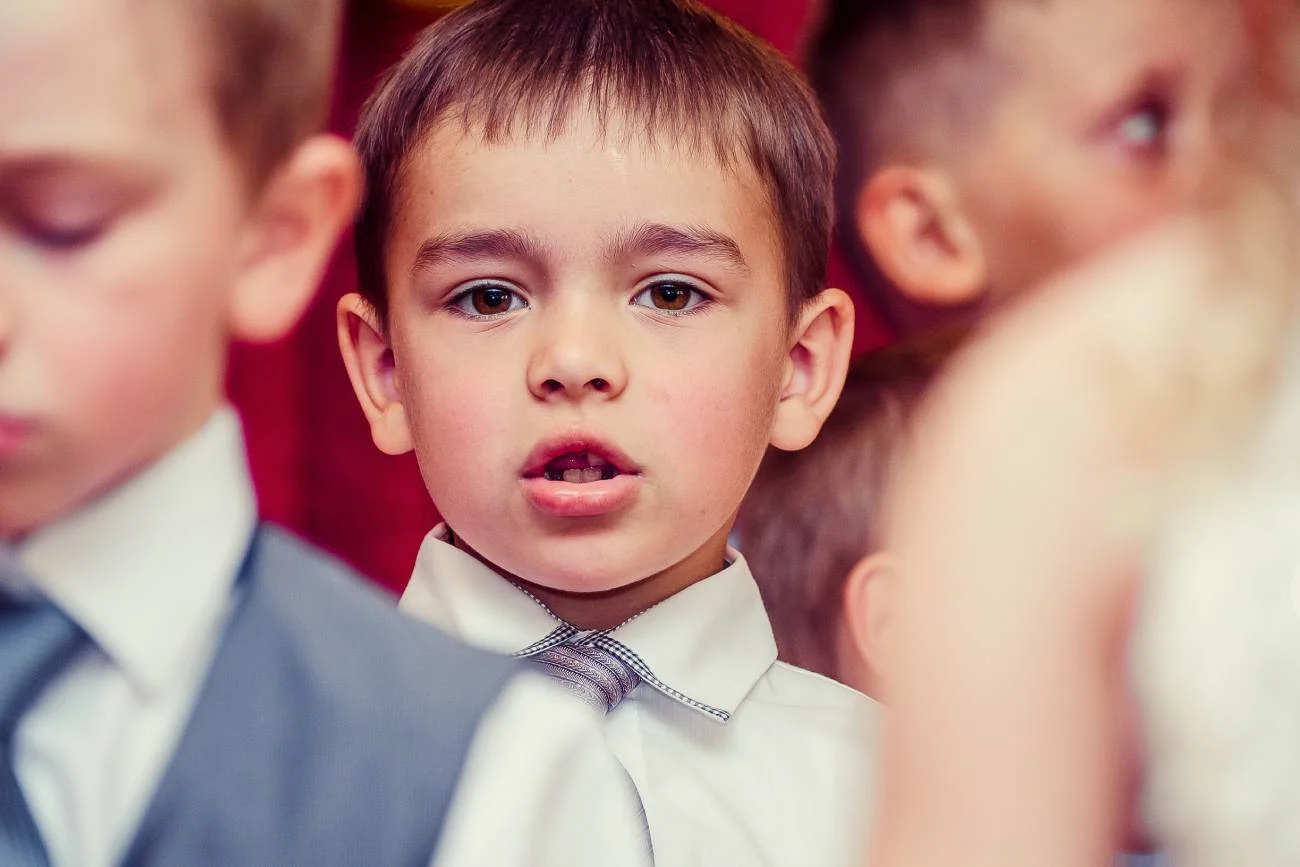 Chłopiec elegancko ubrany śpiewa na Dniu Babci w przedszkolu.