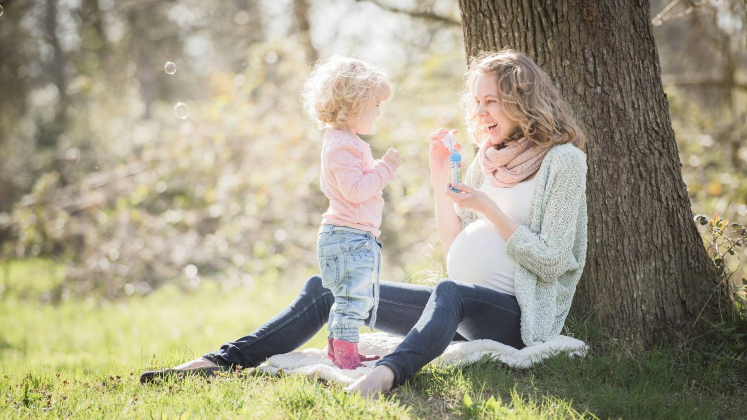 mama w ciąży bawi się z dzieckiem bańkami mama w ciąży bawi się z dzieckiem bańkami
