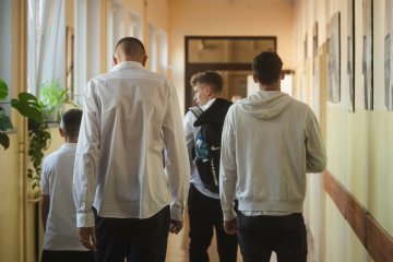 Uczniowie idą szkolnym korytarzem.