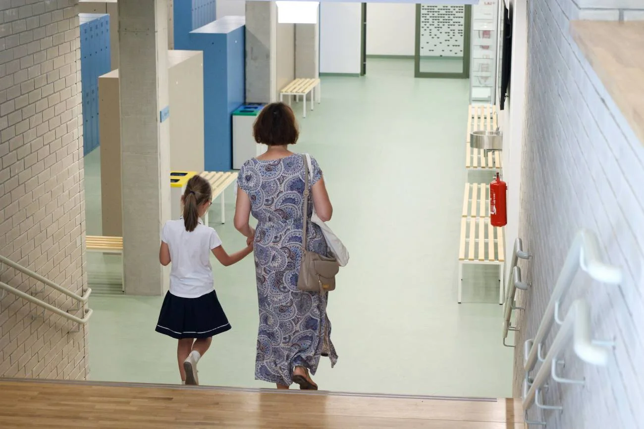 Uczennica idzie z mamą na rozpoczęcie roku szkolnego.