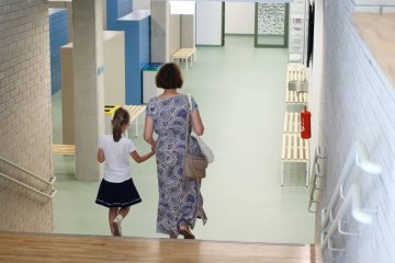 Uczennica idzie z mamą na rozpoczęcie roku szkolnego.