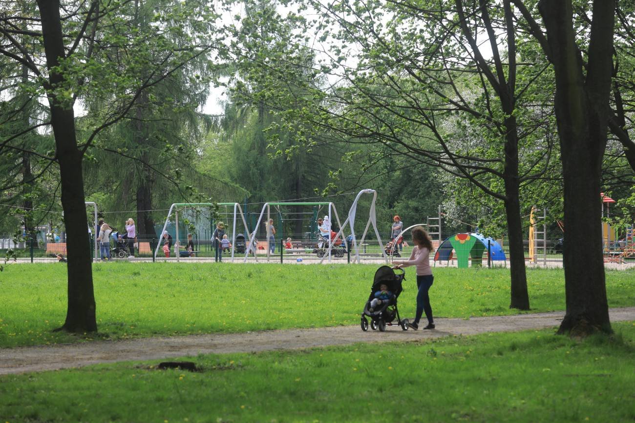 mama z dzieckiem idzie na plac zabaw w parku