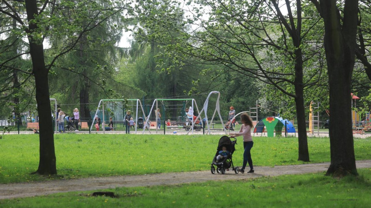 mama z dzieckiem idzie na plac zabaw w parku