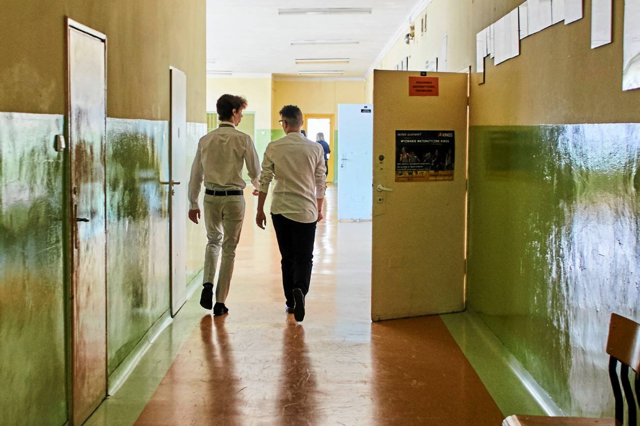 uczniowie idą szkolnym korytarzem