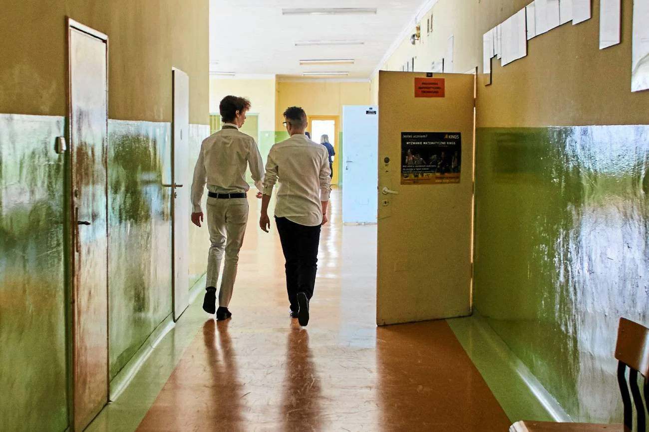 uczniowie idą szkolnym korytarzem
