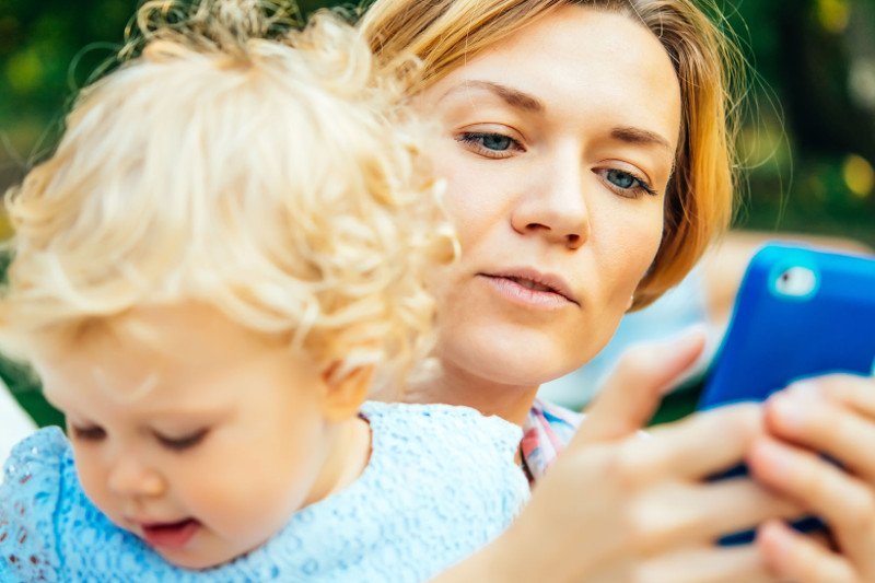 Mama używa telefonu podczas zabawy z dzieckiem