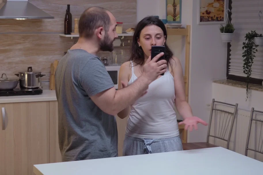 Przemoc ekonomiczna bywa równie dotkliwa jak każdy inny rodzaj przemocy Na zdjęciu widać mężczyznę, który pokazuje kobiecie telefon. Ma zdenerwowaną minę