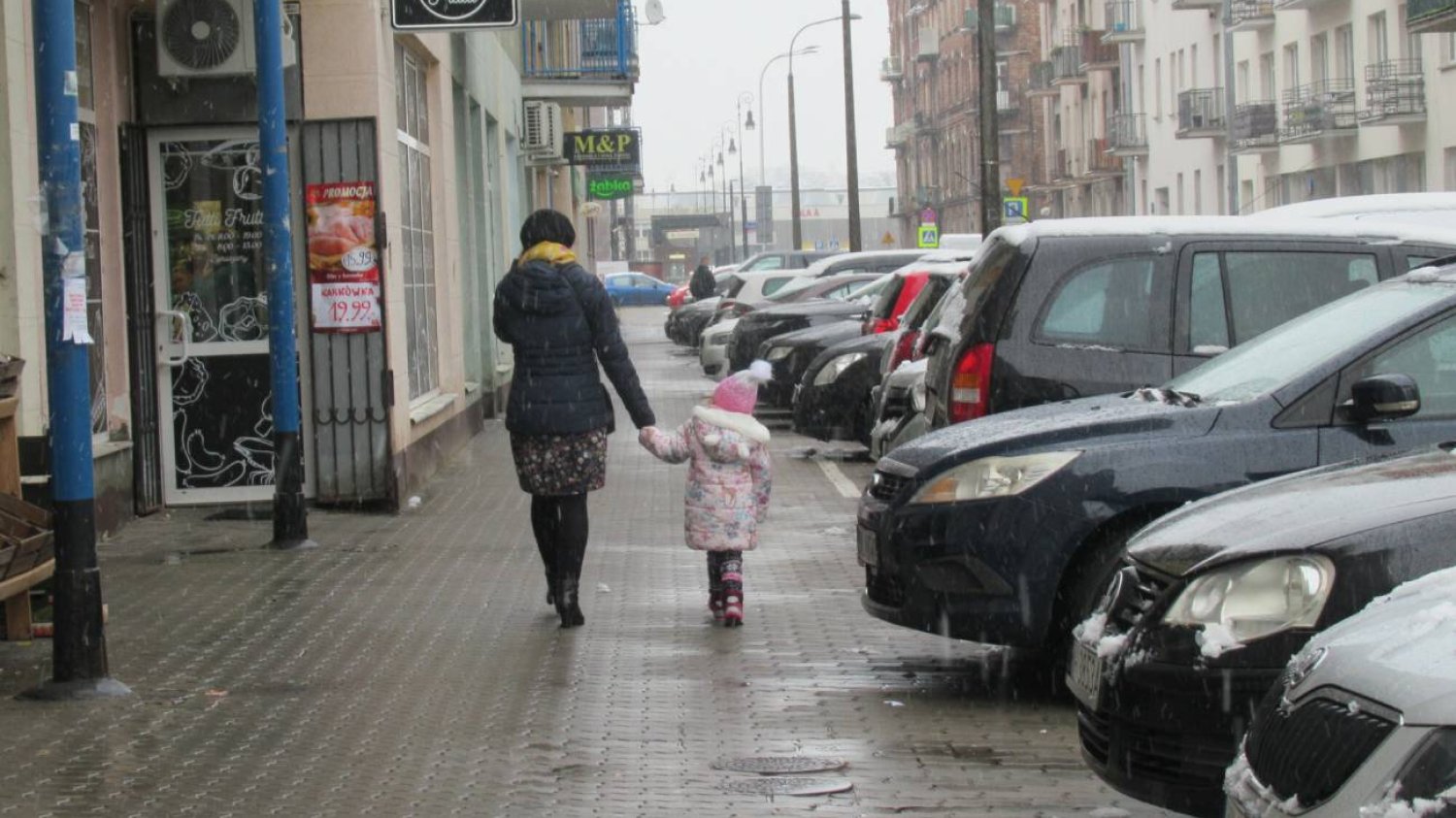 Kobieta idąca przez miasto z dzieckiem.