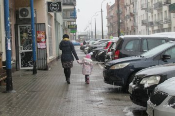 Kobieta idąca przez miasto z dzieckiem.