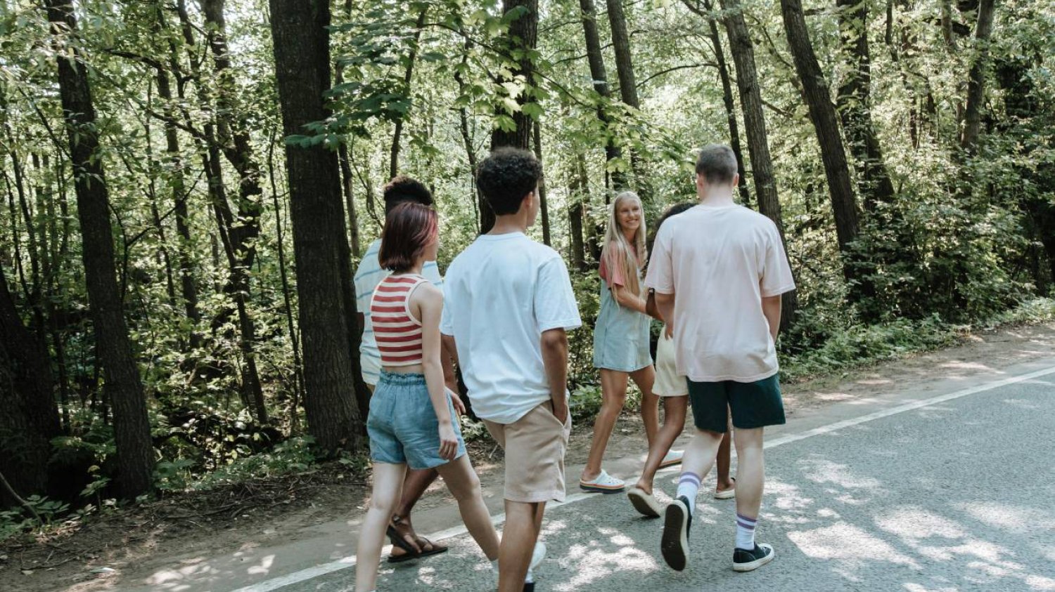 Grupa nastolatków rozmawia i idzie przez park.