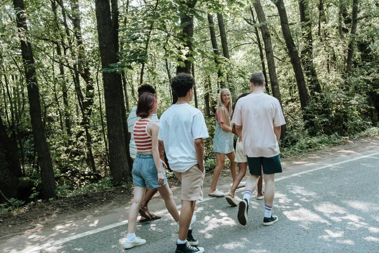 Grupa nastolatków rozmawia i idzie przez park.