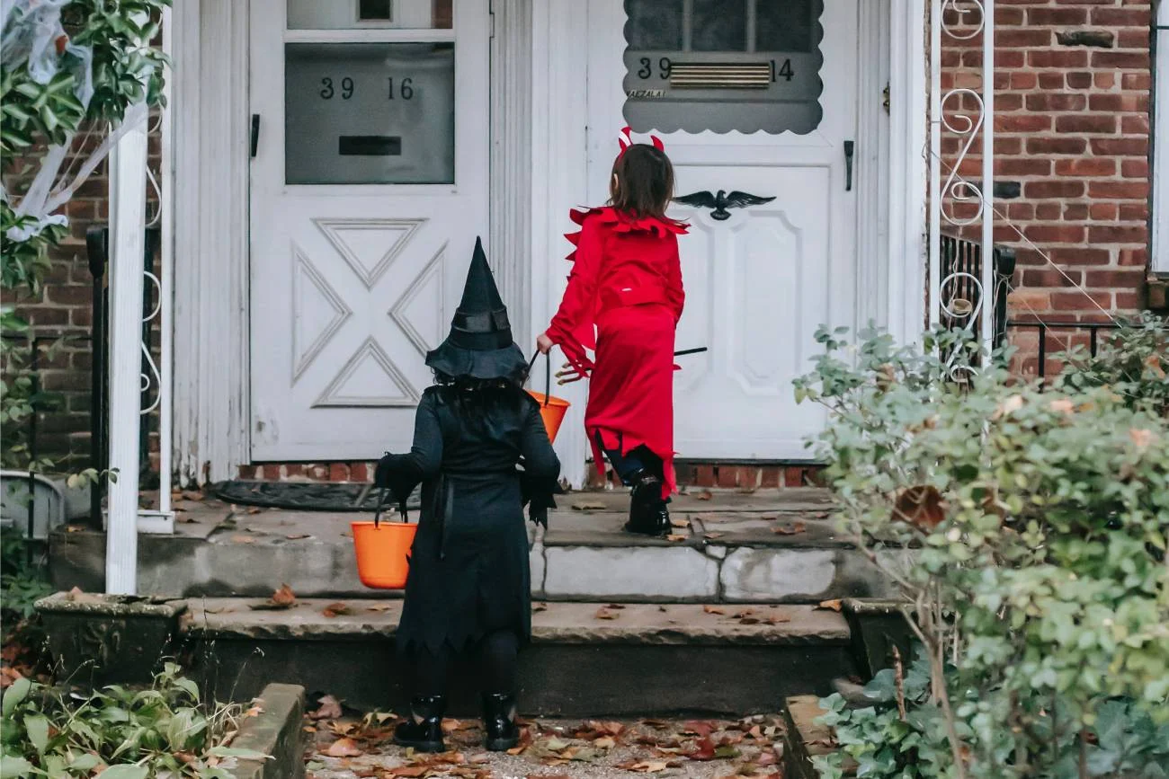 Dzieci pukają do drzwi w przebraniach na Halloween.