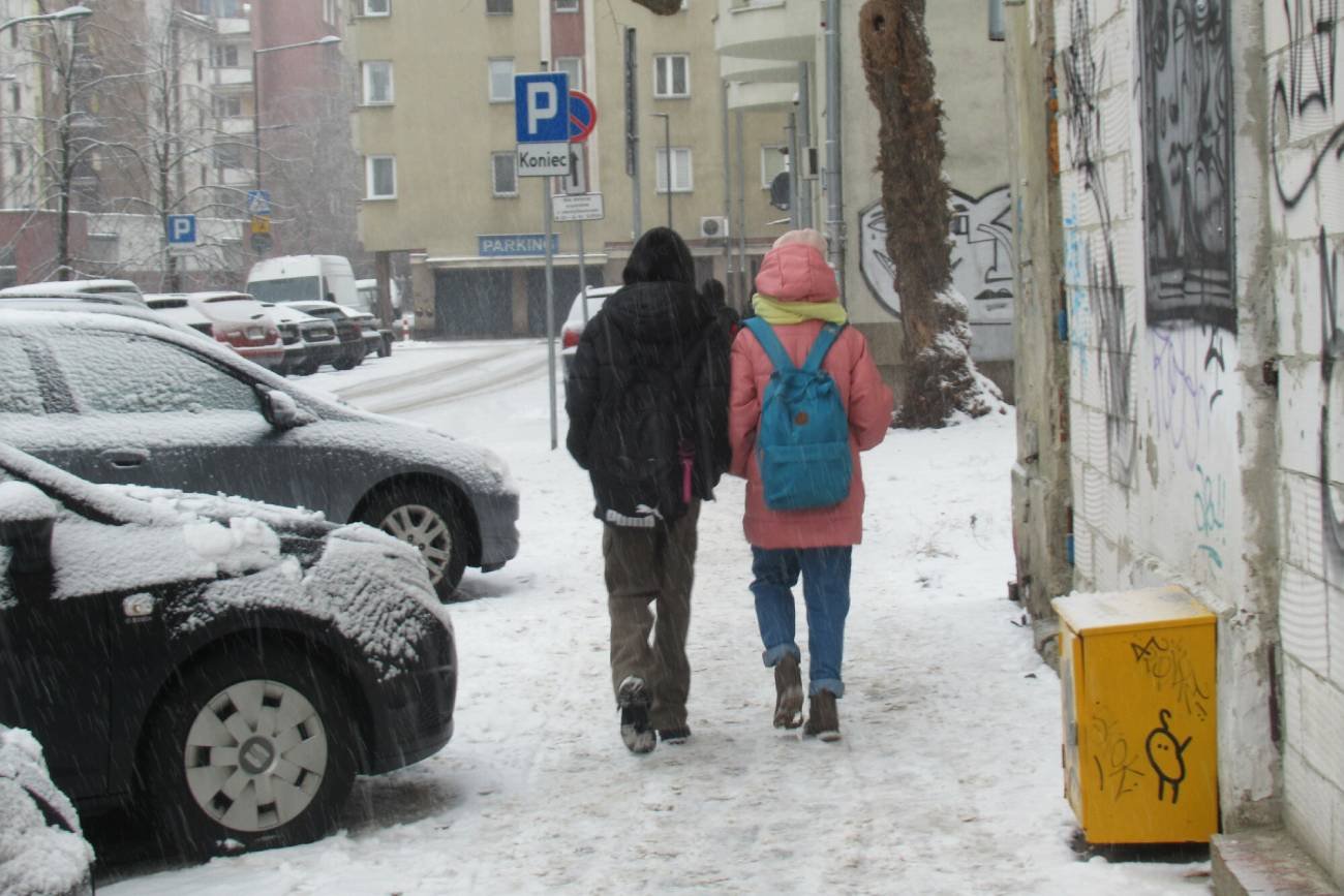 Młodzież z plecakami wraca ze szkoły.