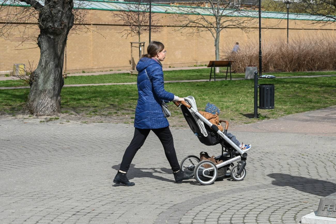 Młoda matka z dzieckiem w wózku na spacerze.