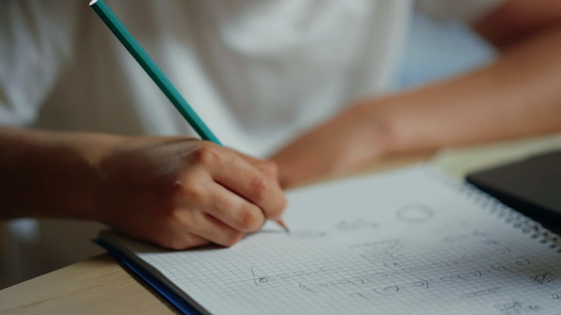 Czy rodzice powinni odrabiać lekcje z dziećmi? Na zdjęciu widać zeszyt i chłopca rozwiązującego zadania.