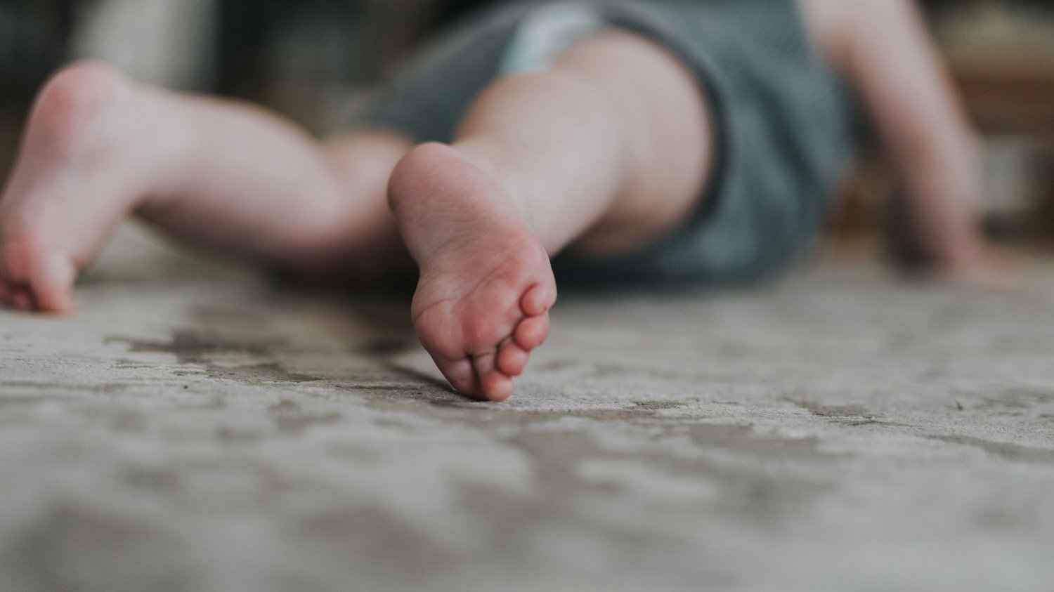 Na zdjęciu dziecko leży na dywanie