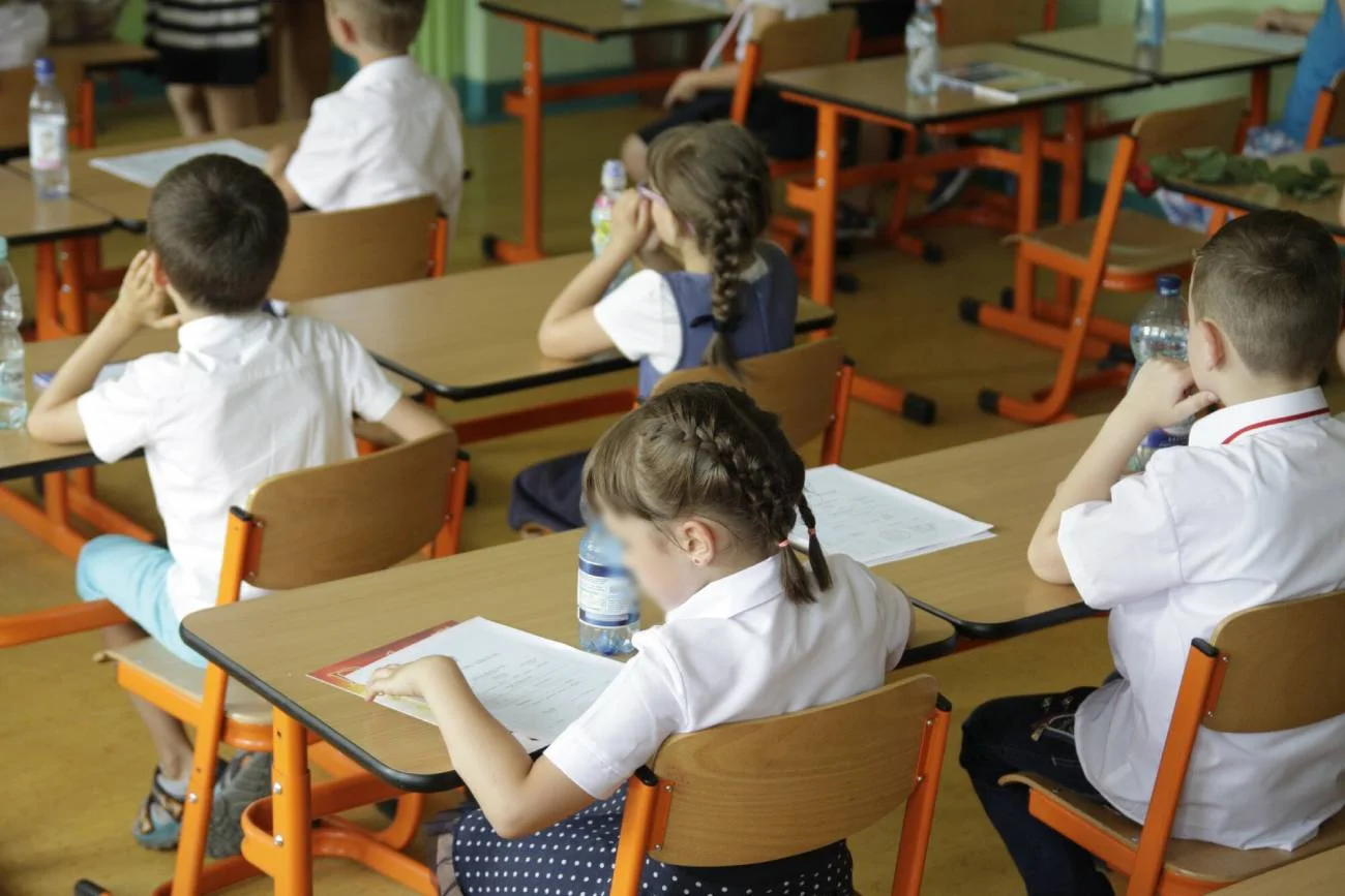 Uczniowie siedzą w ławkach podczas zakończenia roku szkolnego.