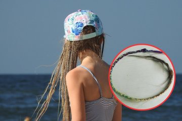 Dziewczynka na wakacjach nad morzem z warkoczykami na głowie.