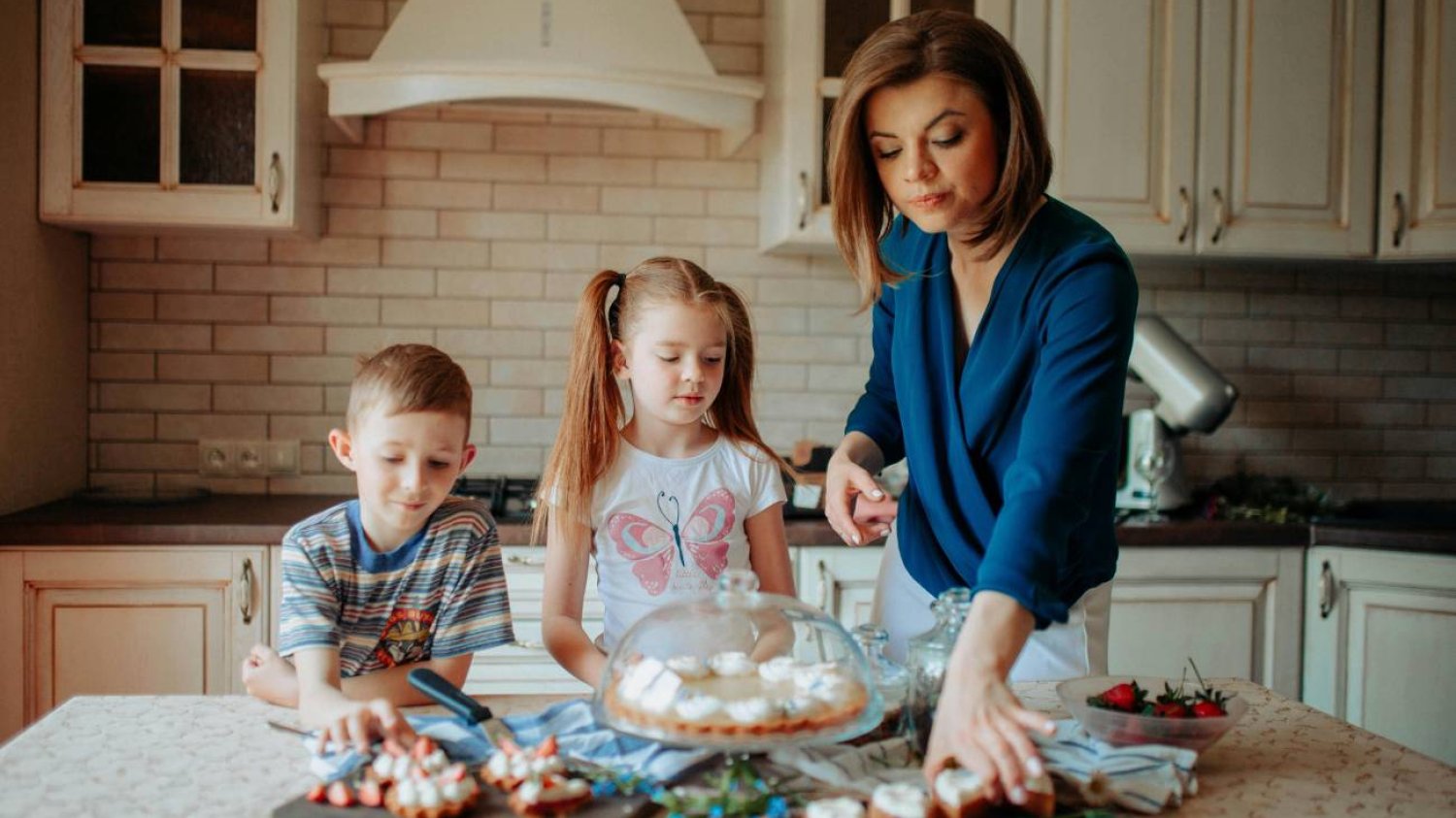 Mama gotuje w kuchni razem z dziećmi.