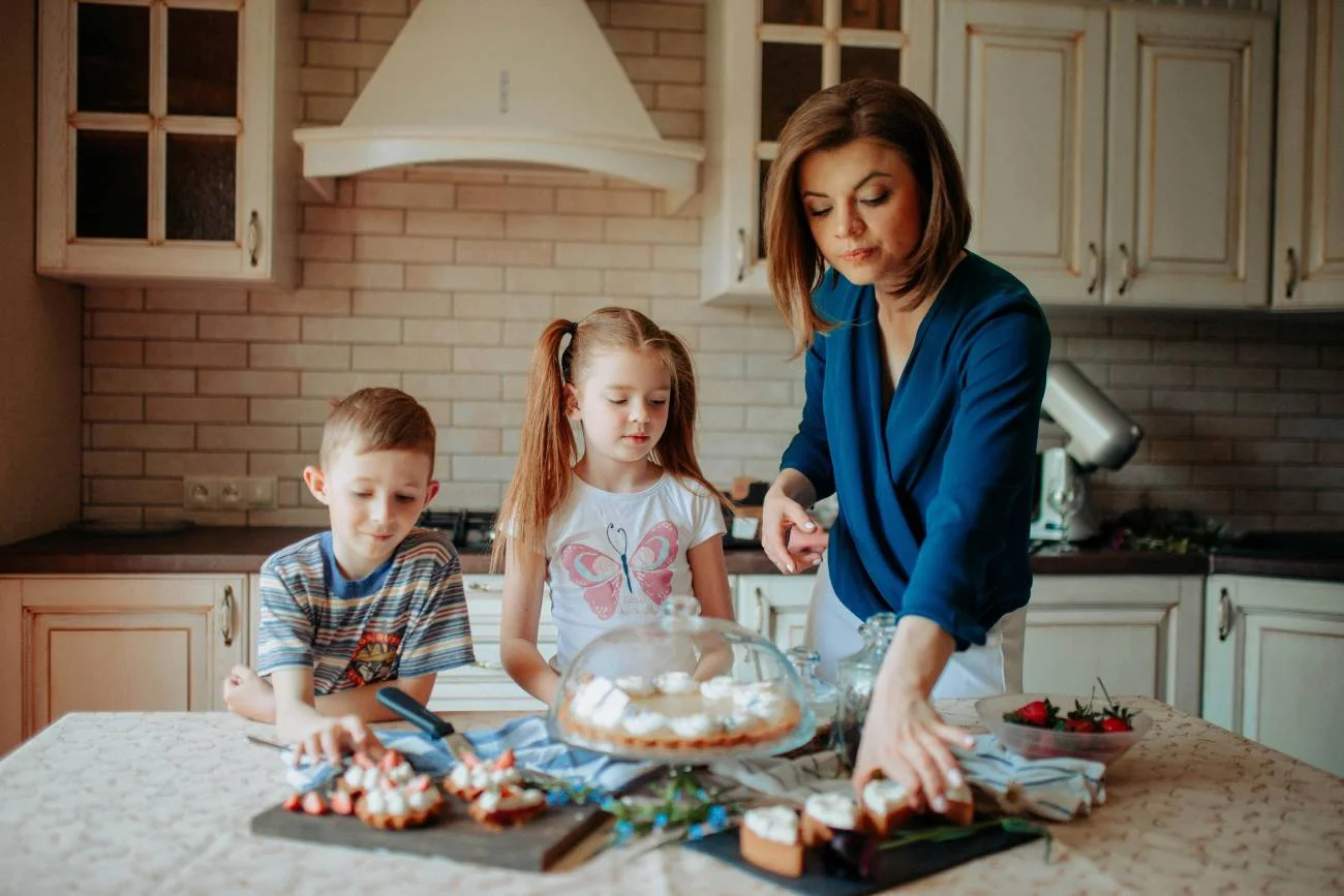 Mama gotuje w kuchni razem z dziećmi.
