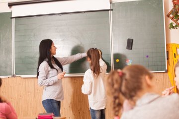 Nauczycielka tłumaczy coś uczennicy przy tablicy. Nauczycielka tłumaczy coś uczennicy przy tablicy.