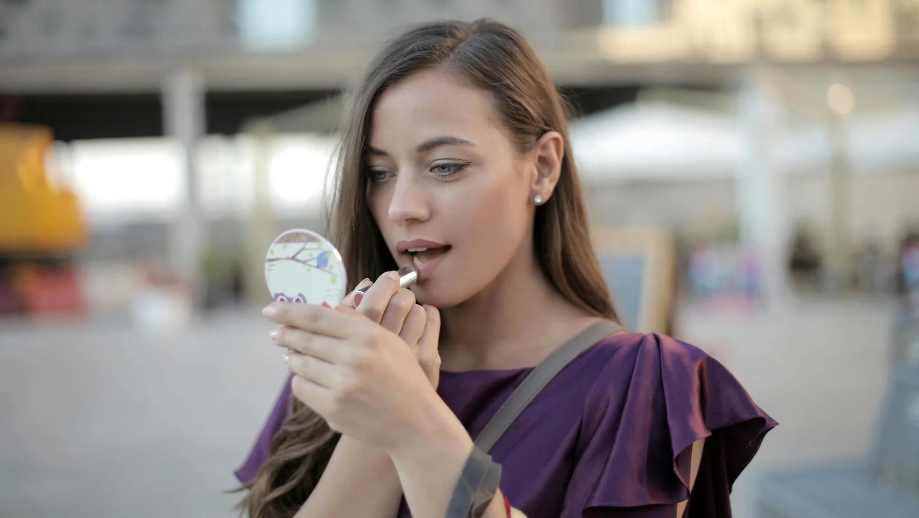 Na zdjęciu kobieta poprawia makijaż.