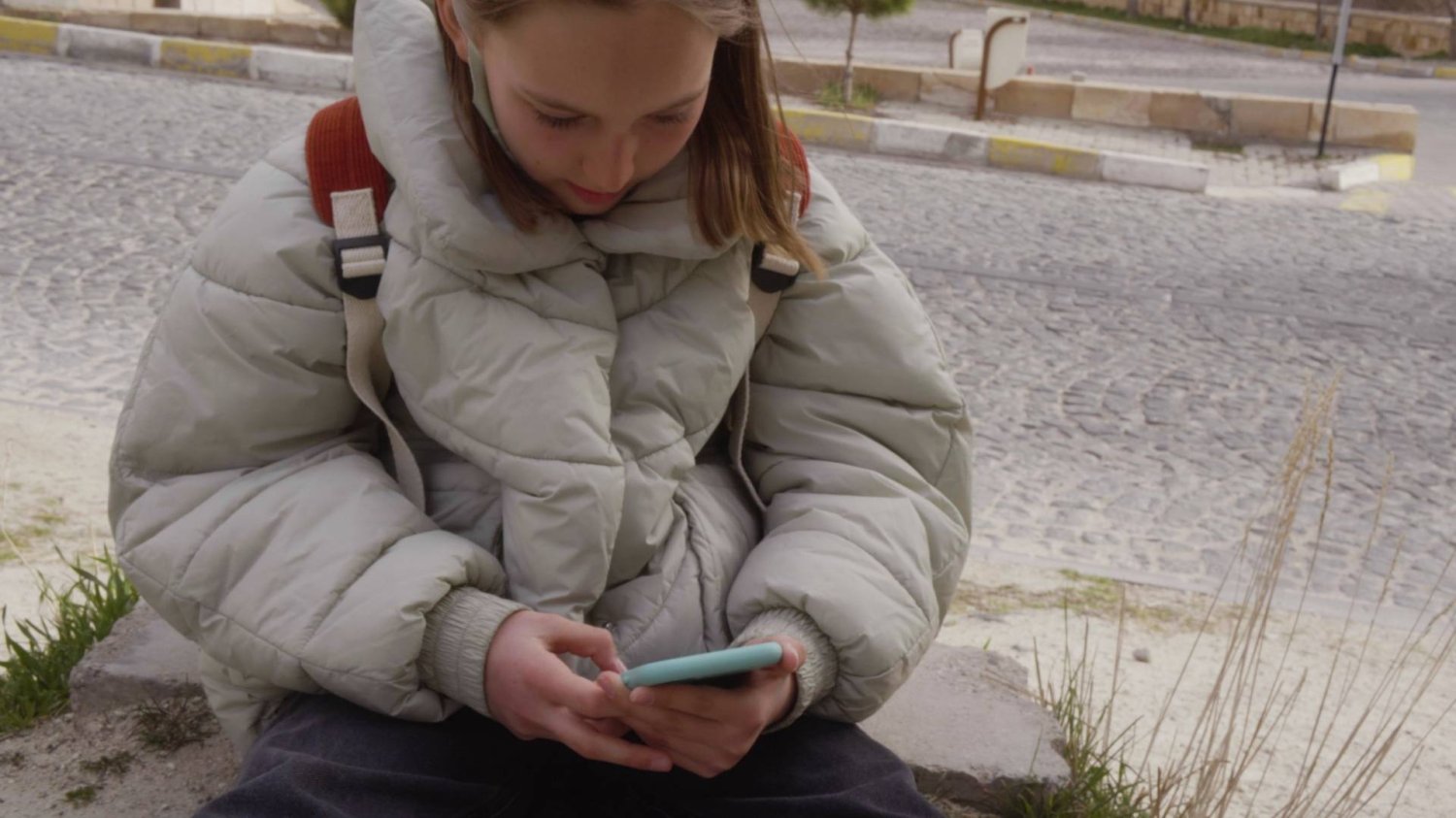 dziewczynka scrolluje smartfona, wpisując pytania do AI