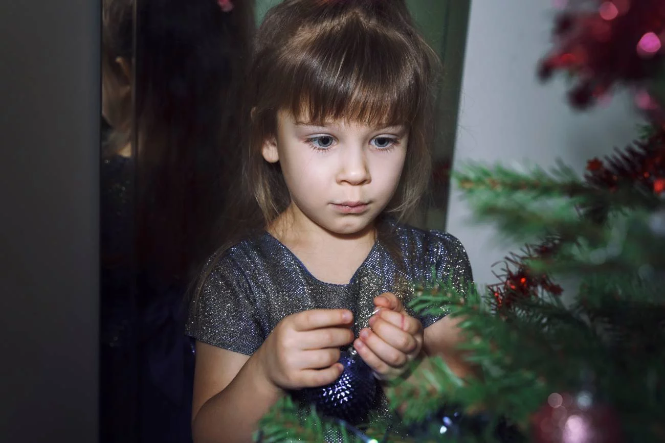 Smutna dziewczynka sama ubiera choinkę. Smutna dziewczynka sama ubiera choinkę.