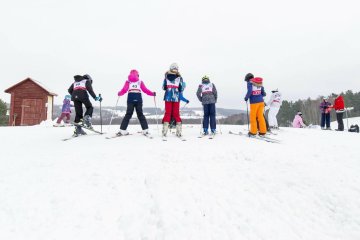 Dzieci na stoku uczą się jeździć na nartach.