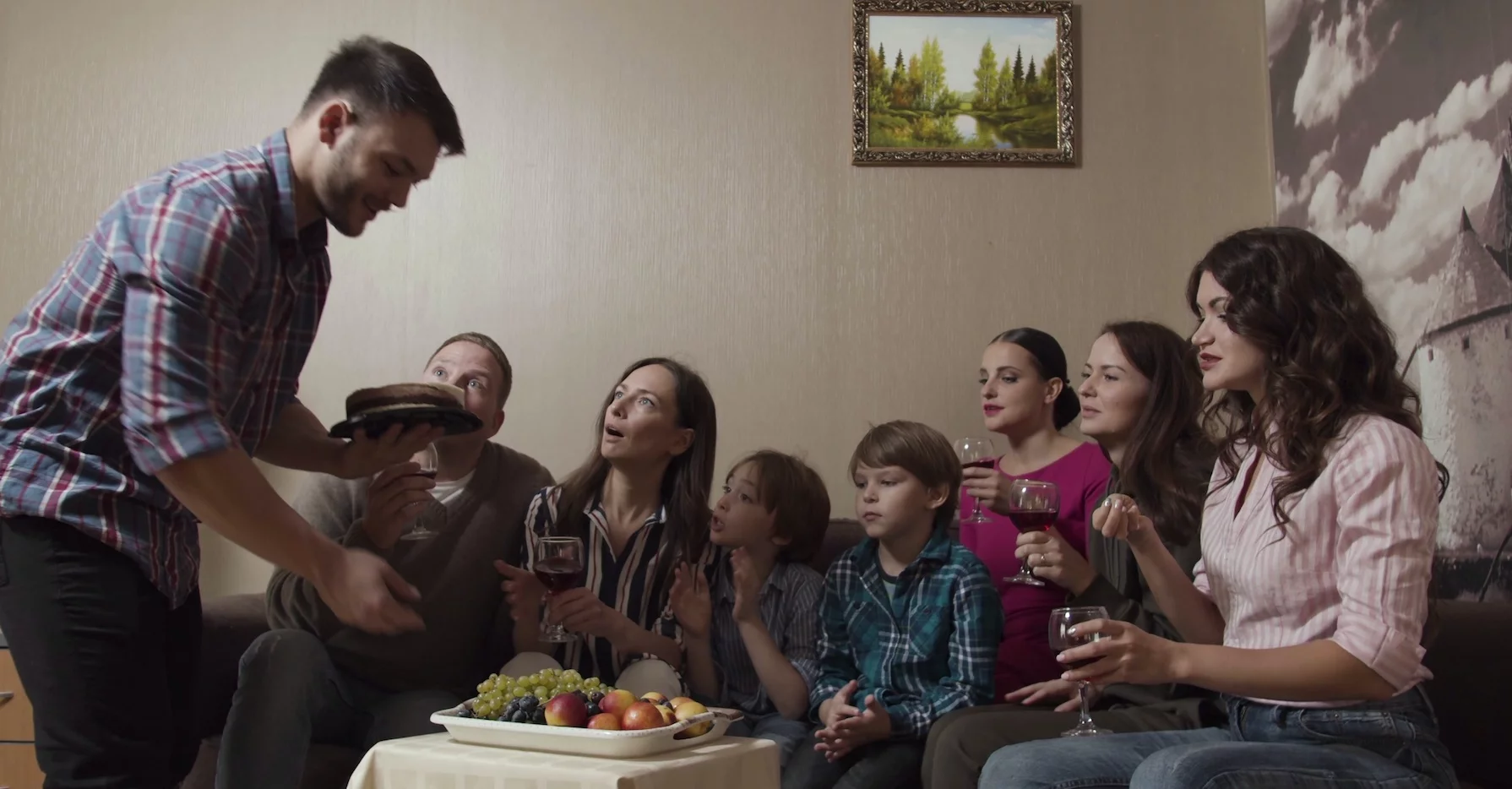 Na zdjęciu duża rodzina siedzie na kanapie.