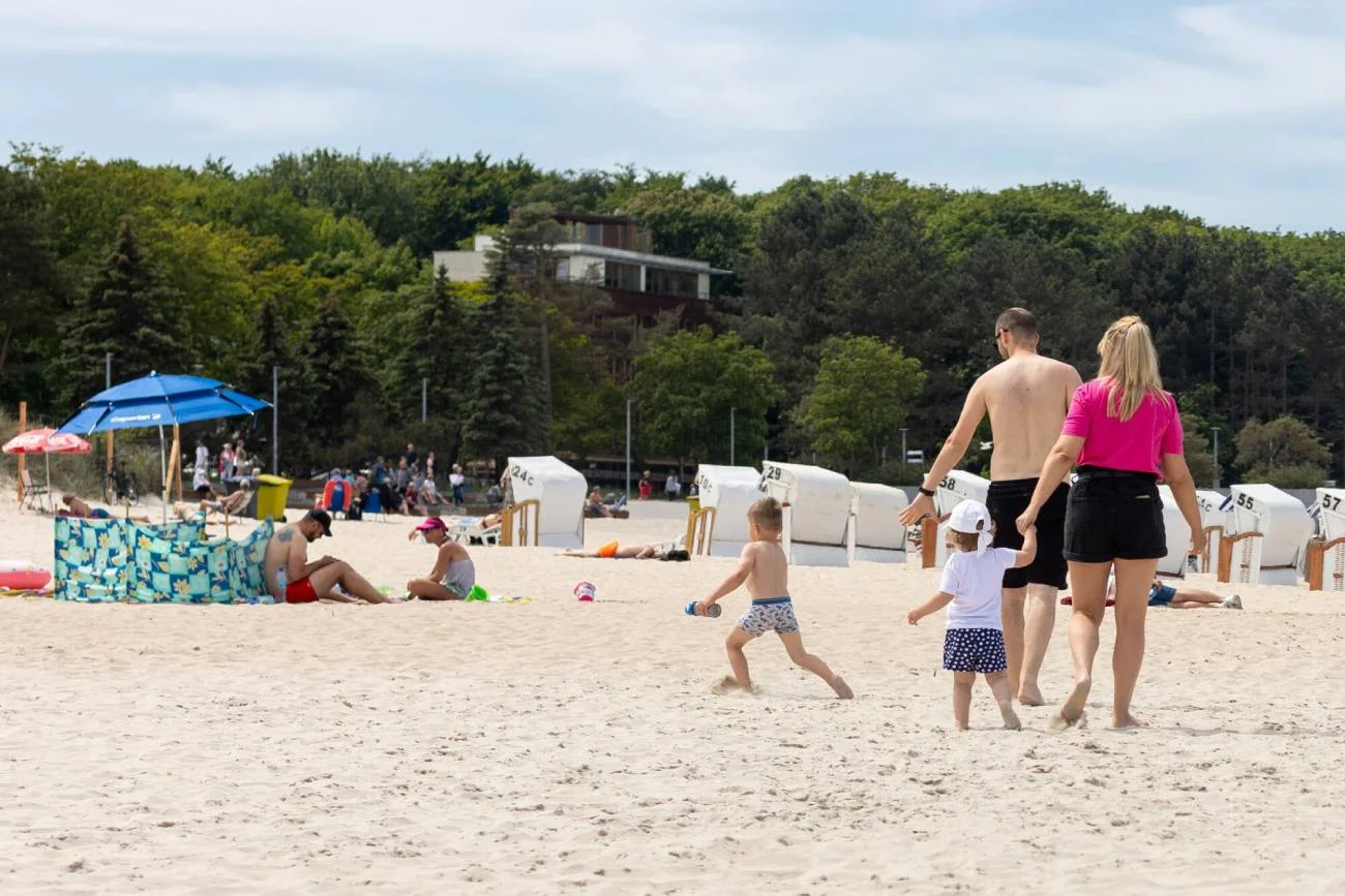 Małżeństwo z dziećmi spaceruje po plaży.